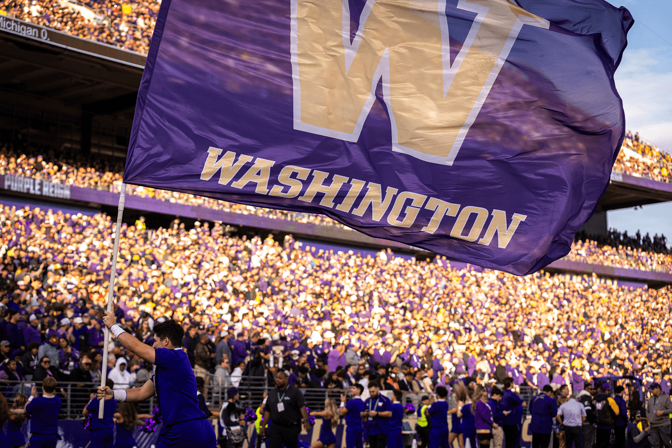 Husky fans waving the Washington flag in a packed stadium